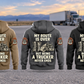 Five complete separated back views of the Trucker Never Ends Vintage Hoodie in Military Green, Kaki, Dark Gray, Black and Dark Blue, arranged left to right against a parked unbranded truck and open-road rest-area background.