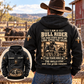 Back view of an adult cowboy wearing the Black Bull Rider Skills and Pride Vintage Hoodie at a ranch corral, with readable cream-and-gold rider artwork and a smaller matching front-view inset.