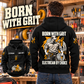 Black Electrician By Choice Vintage Hoodie shown on a back-facing model in a softly sunlit electrical workshop, with a smaller complete front inset and cream BORN WITH GRIT lettering.
