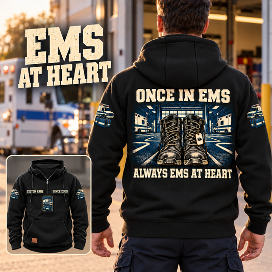 Black EMS Once and Always Vintage Hoodie worn from the back at an off-duty ambulance station, showing boots and ambulance-bay artwork, with a smaller front-view inset.