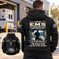 Black EMS Skills and Pride Vintage Hoodie worn from behind at a quiet ambulance station, with readable cream-and-navy back artwork and a smaller complete front-view inset.