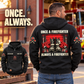 Black Firefighter Once and Always Vintage Hoodie with boots-and-hose back artwork on an off-duty model beside a fire-station bench, plus front inset.