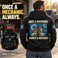 Black Mechanic Once and Always Vintage Hoodie worn from the back at a garage entrance, showing blue boot-and-gear artwork, with a complete front inset.