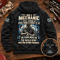 Black Mechanic Skills and Pride Vintage Hoodie laid back-up on a garage workbench, with cream-and-blue mechanic artwork and a smaller front-view inset.