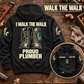 Black Plumber Proud Walk Vintage Hoodie on a plumbing workbench, with large cream boots artwork and I WALK THE WALK / PROUD PLUMBER lettering, plus a smaller front view.