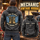Mechanic Walk the Walk Badge Vintage Hoodie in Dark Gray, back left front cutout composition with faithful front and back artwork in a tidy auto workshop with a vintage vehicle blurred behind.