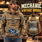 Mechanic Never Ends Vintage Hoodie in Kaki, front left back inset composition with faithful front and back artwork in a tidy auto workshop with a vintage vehicle blurred behind.