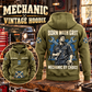 Mechanic By Choice Vintage Hoodie in Military Green, back right front inset composition with faithful front and back artwork in a tidy auto workshop with a vintage vehicle blurred behind.
