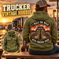 Trucker Walk the Walk Badge Vintage Hoodie in Military Green, back right front inset composition with faithful front and back artwork in a quiet roadside truck stop with a parked tractor cab blurred behind.