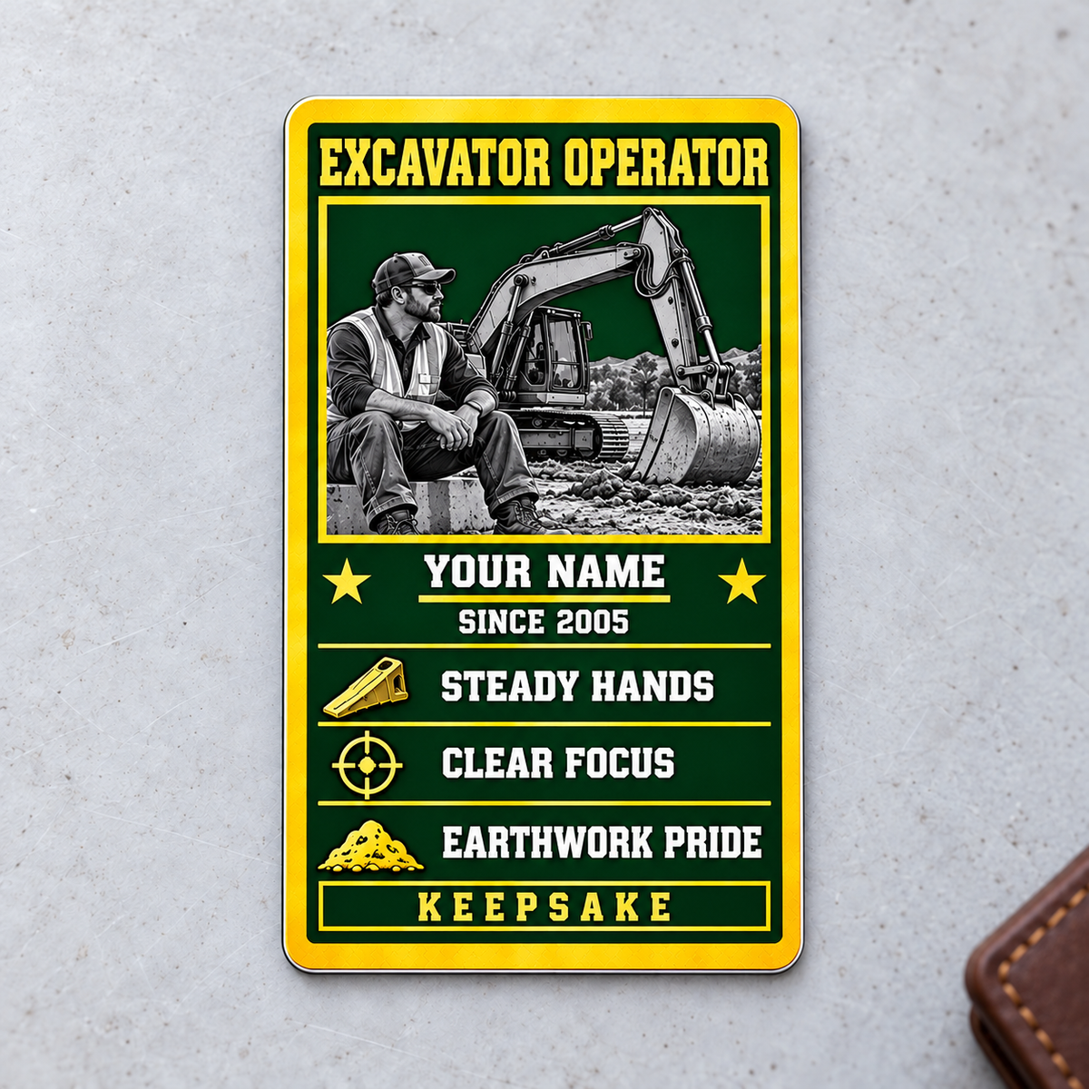 Front of the Trade Legend Collectible Excavator Operator aluminum wallet card on a light concrete surface.