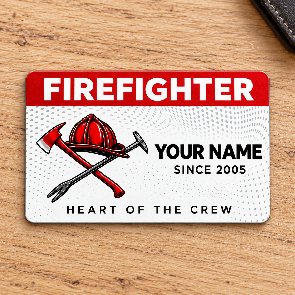 Front of red-header Firefighter aluminum wallet card with helmet and crossed tools on pale oak.