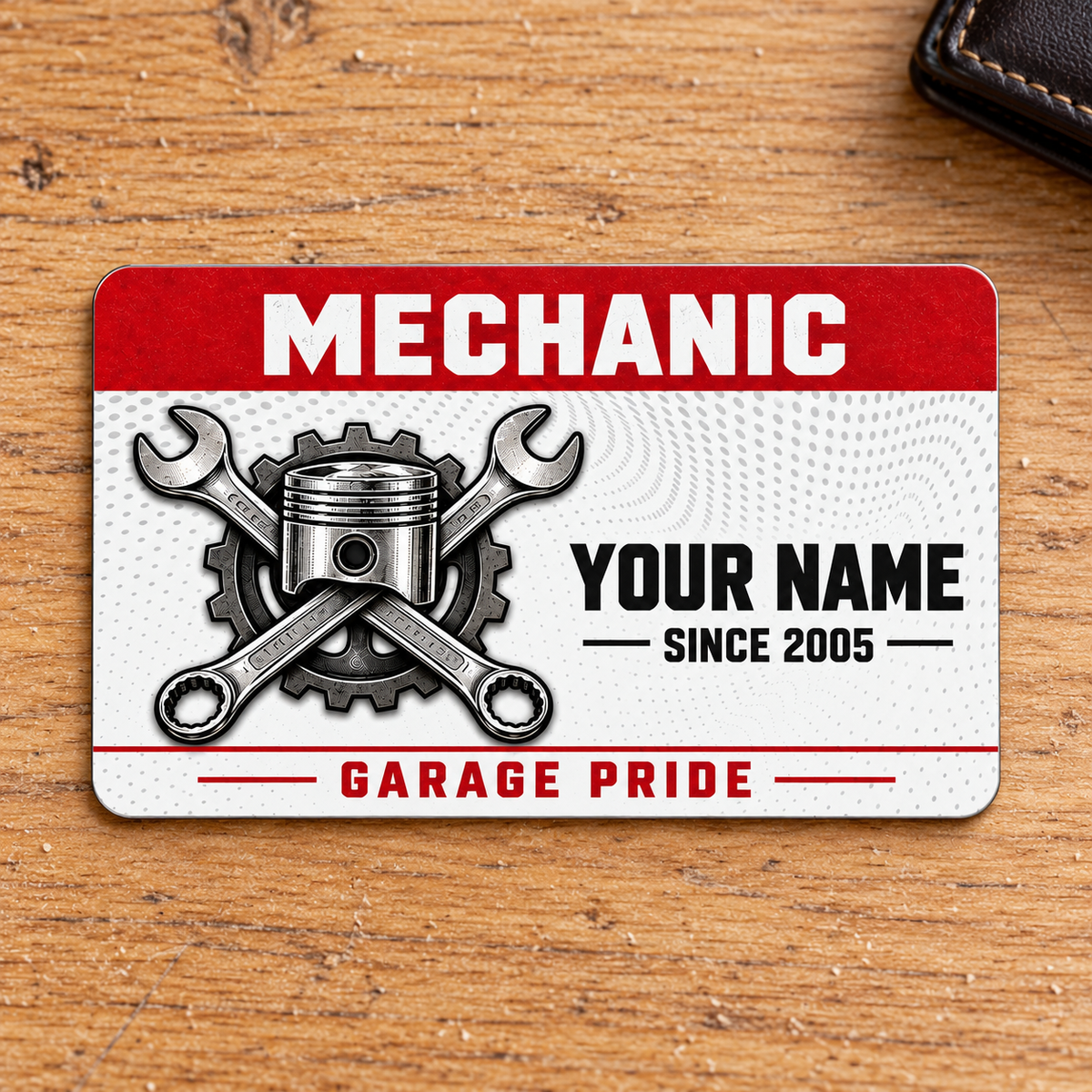 Front of Mechanic Red Header aluminum wallet card on a warm oak desk.