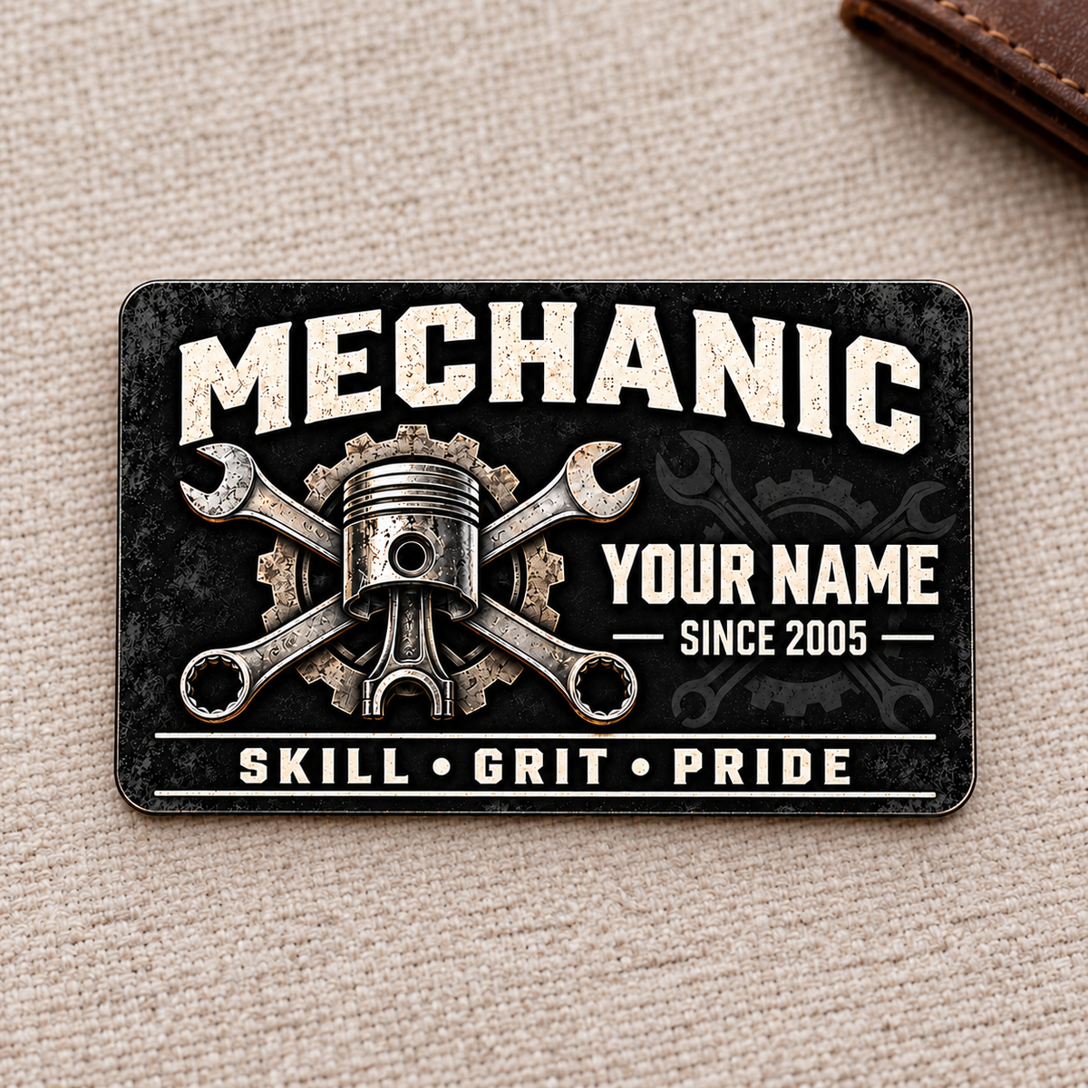 Front of Mechanic Midnight Pride aluminum wallet card on warm woven fabric.
