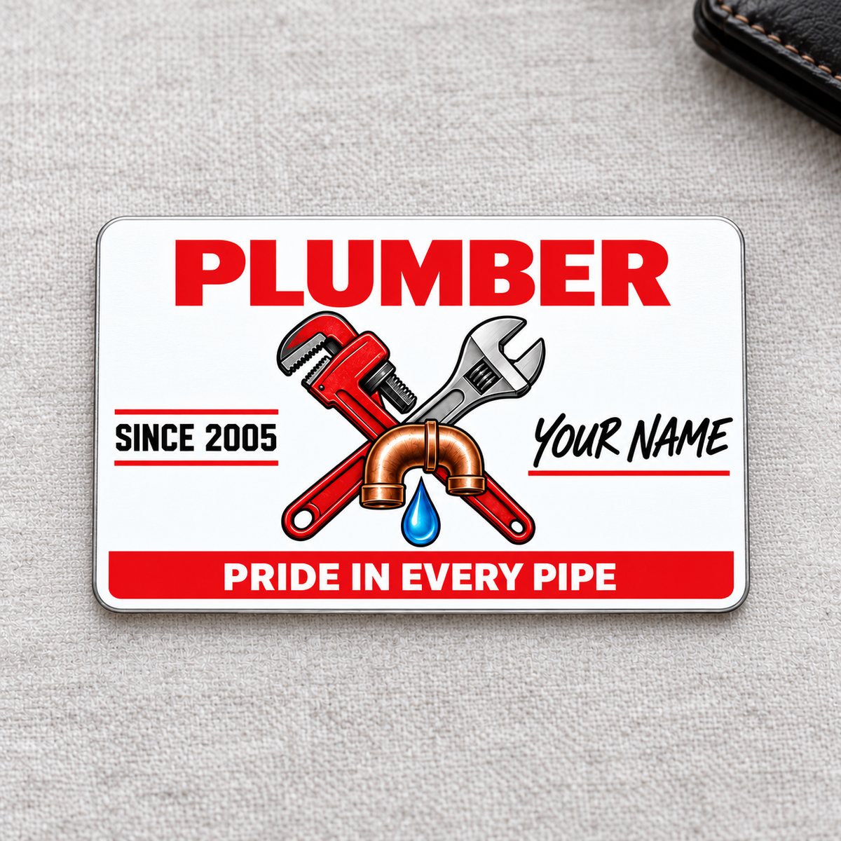 Plumber Signature Classic aluminum wallet card, front design on soft gray fabric.
