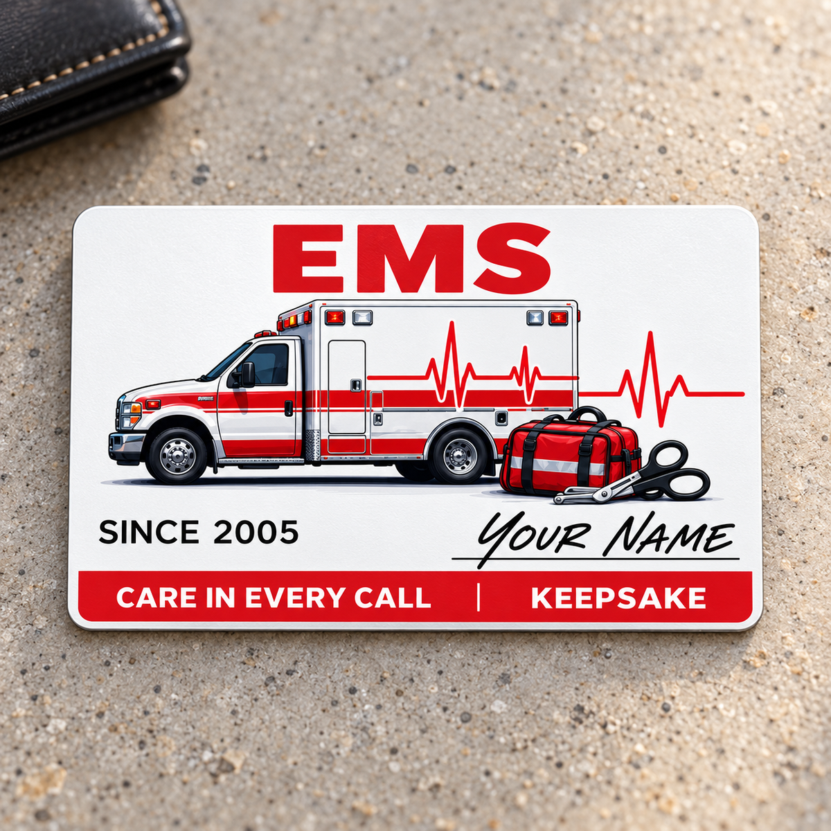 EMS Signature Classic aluminum wallet card, single front with ambulance and script name artwork on warm gray concrete.