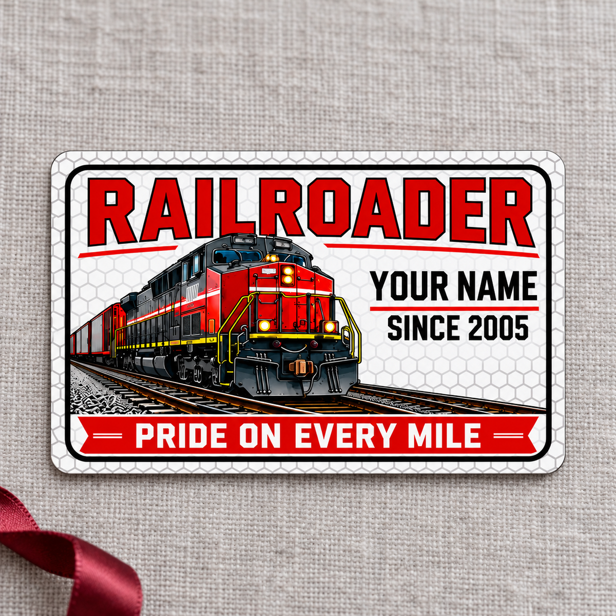 Railroader Honeycomb Pride aluminum wallet card, front face on gray linen with a burgundy gift ribbon.