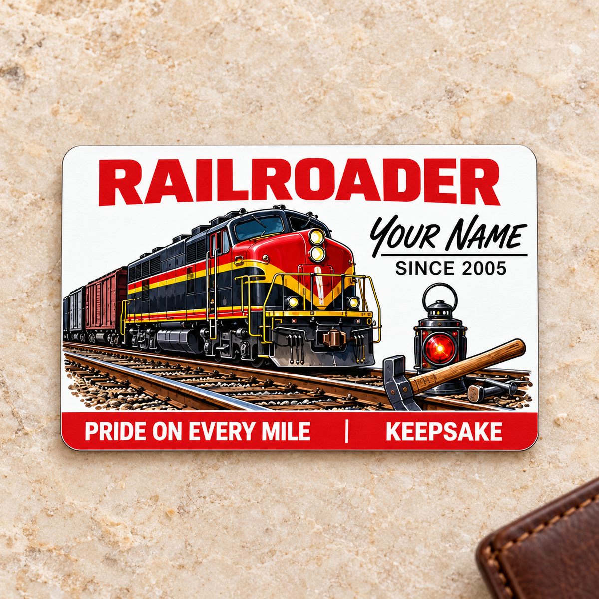 Railroader Signature Classic aluminum wallet card, front face on cream stone beside a brown wallet.