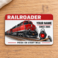 Railroader Red Header aluminum wallet card, front face on pale oak beside cream linen.