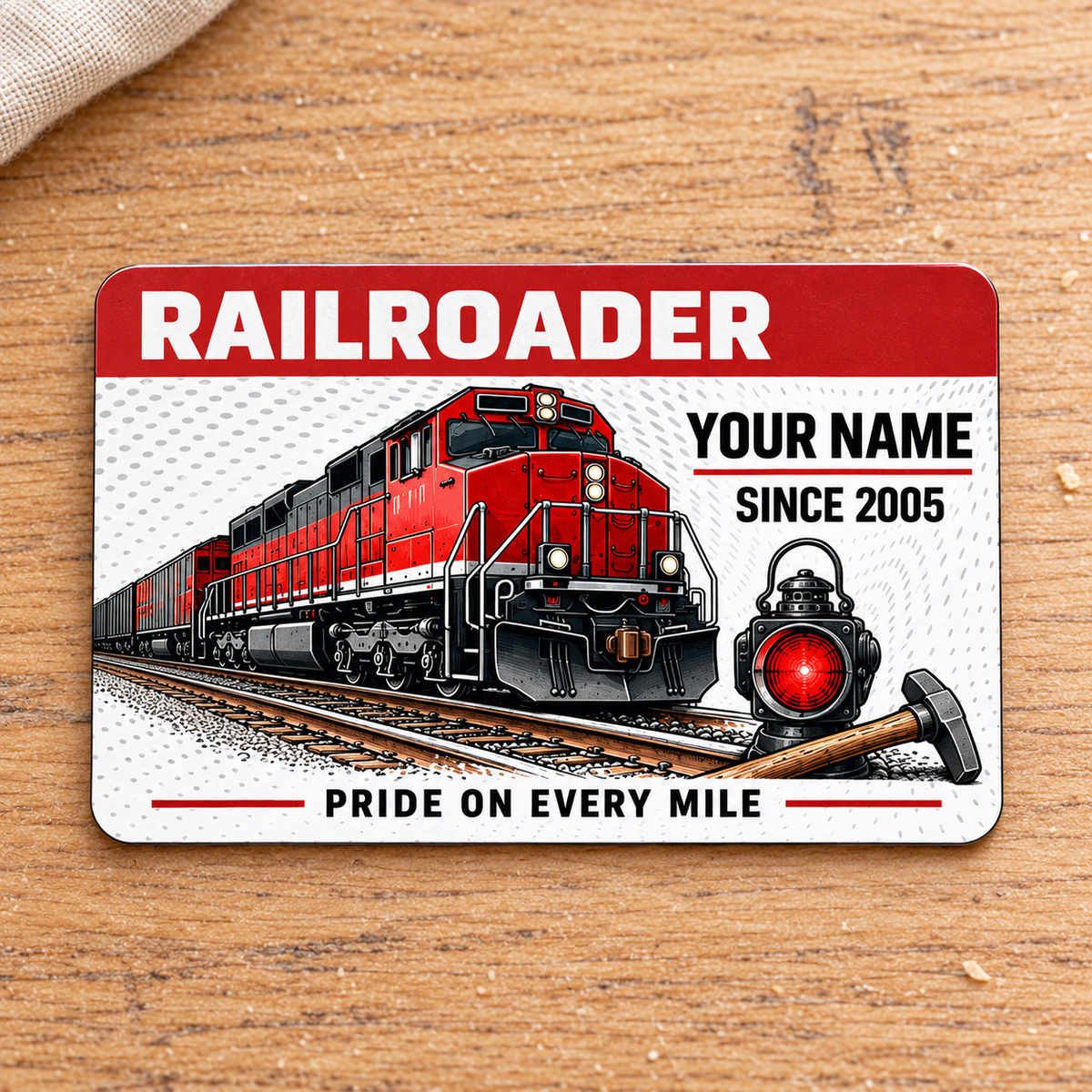 Railroader Red Header aluminum wallet card, front face on pale oak beside cream linen.