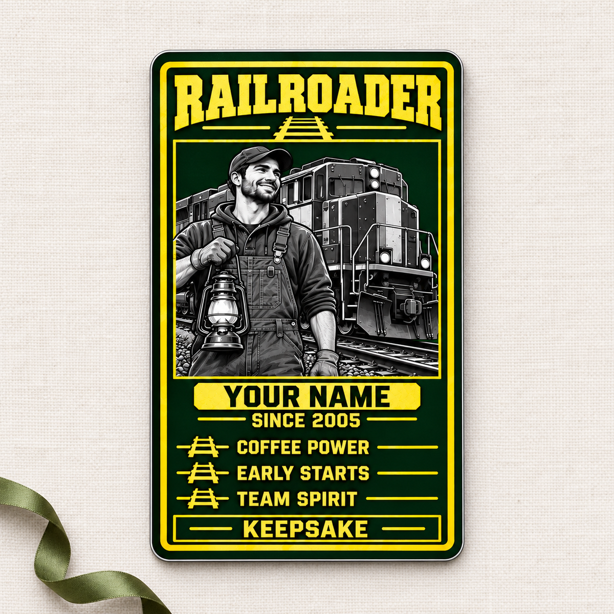 Railroader Trade Legend portrait aluminum wallet card front on cream linen with an olive ribbon, showing grayscale worker and locomotive artwork.
