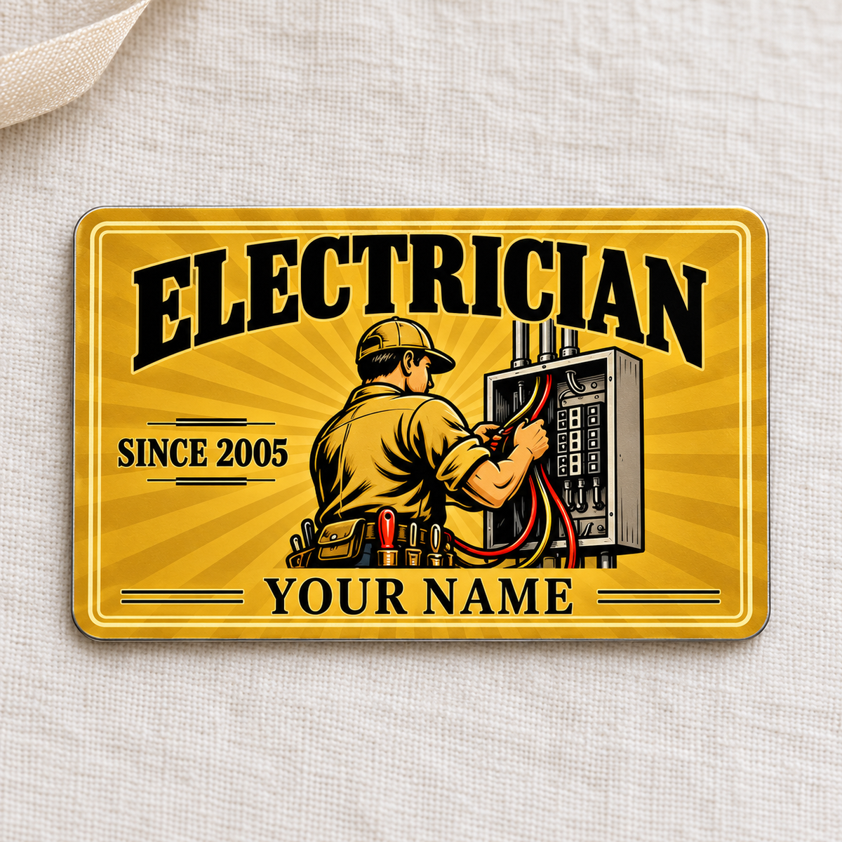 Electrician Golden Milestone aluminum wallet card, front view on cream linen