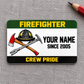 Green-band firefighter aluminum wallet card with helmet and crossed tools on gray fabric.