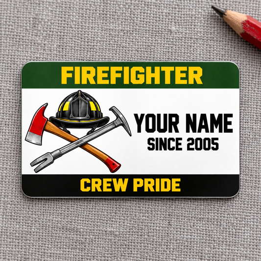 Green-band firefighter aluminum wallet card with helmet and crossed tools on gray fabric.