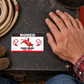 Bull Riding/Rodeo Red Monochrome aluminum wallet card on a dark tack trunk beside an adult hand
