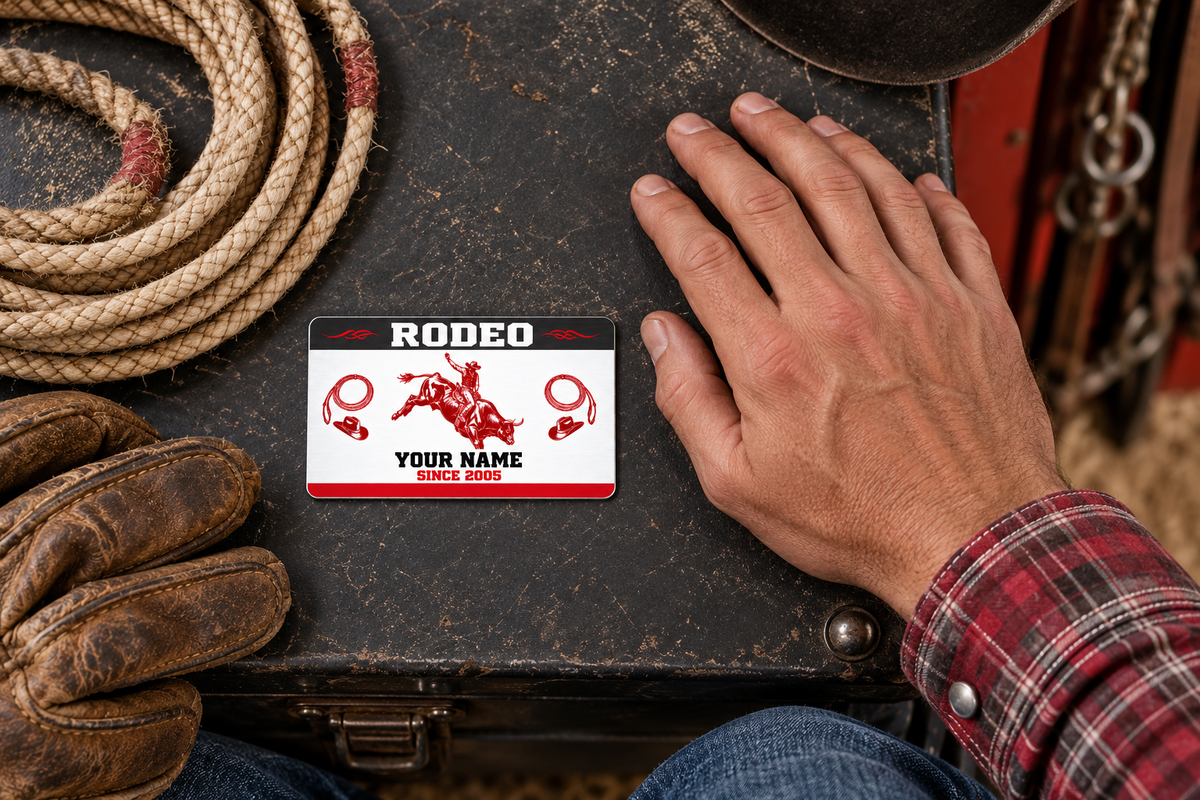 Bull Riding/Rodeo Red Monochrome aluminum wallet card on a dark tack trunk beside an adult hand