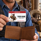 Adult rodeo rider holding the Red Header wallet card above a tan bifold wallet in a tack room