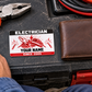 Electrician Red Monochrome wallet card on a toolbox beside pliers, disconnected cable and a closed brown wallet