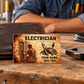 Electrician Sepia Legacy aluminum wallet card leaning against a worn brown wallet on a timber workbench