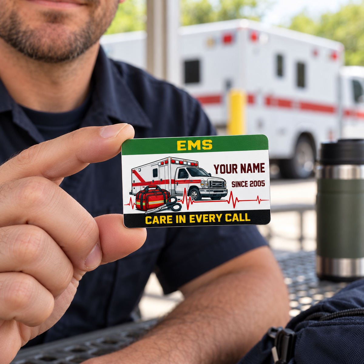 Adult male responder holding the Green Band EMS wallet card during a station break, with a thermos nearby.