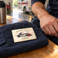 Ivory Heritage EMS card resting on a folded navy work jacket beside an adult responder's hand at the station.