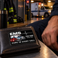 Midnight Pride EMS keepsake card on a closed leather wallet beside an adult responder's hand in a softly lit station.