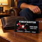 Black firefighter wallet card beside a dark leather wallet on a warm-lit table with a seated adult man behind it.