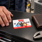 HVAC Signature Modern aluminum wallet card lying flat on a dark tool cabinet beside an adult technician's hand and a closed leather wallet.