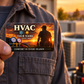 HVAC Sunset Workday aluminum wallet card held at its lower-left corner near an adult technician's shirt pocket, with condenser equipment in warm evening light.