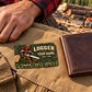 Logger wallet card in a forest logging rest area with an adult man and leather wallet.