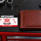 Mechanic Red Monochrome aluminum wallet card shown at wallet scale in an automotive workshop setting.