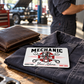 Mechanic Signature Classic aluminum wallet card on a folded work shirt beside a brown wallet in a garage.