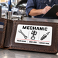 Mechanic Minimal Grid aluminum wallet card resting within one panel of an open leather bifold wallet in a garage.
