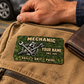 Mechanic Rugged Field aluminum wallet card on a canvas work bag beside a brown leather wallet in a garage.