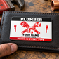 The printed front of the Plumber Red Monochrome Craft aluminum wallet card shown in an occupational lifestyle setting with an adult worker.