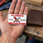 The printed front of the Plumber Signature Classic aluminum wallet card shown in an occupational lifestyle setting with an adult worker.