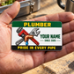 The printed front of the Plumber Green Band Appreciation aluminum wallet card shown in an occupational lifestyle setting with an adult worker.