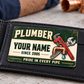 The printed front of the Plumber Heritage Band Appreciation aluminum wallet card shown in an occupational lifestyle setting with an adult worker.