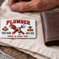 The printed front of the Plumber Minimal Tool Grid aluminum wallet card shown in an occupational lifestyle setting with an adult worker.