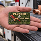 The printed front of the Plumber Rugged Field Pride aluminum wallet card shown in an occupational lifestyle setting with an adult worker.