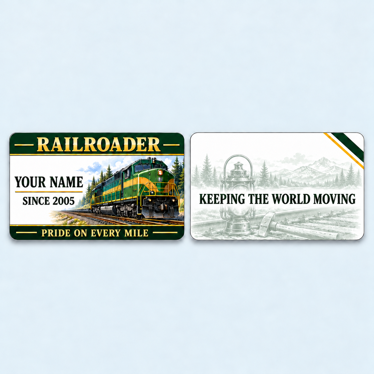 Railroader Heritage Band aluminum keepsake wallet card, front and reverse views. A deep-green header and fine gold-colored rules frame a forest railway scene, with name-and-year lettering to the left of the locomotive. A softly faded lantern-and-tools illustration on the reverse surrounds the message KEEPING THE WORLD MOVING.